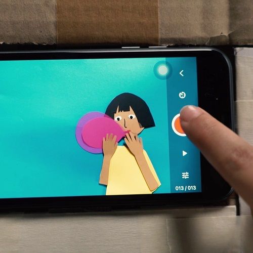 Ein Smartphone mit Stop-Motion-App zeigt eine Figur aus Pappe, die einen Ballon aufbläst.